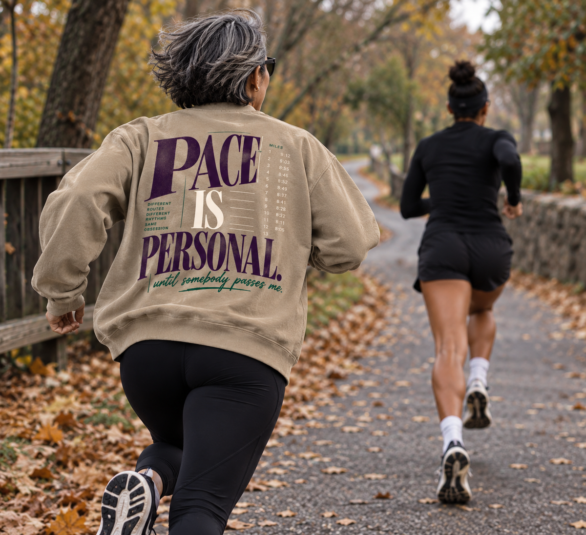 Race Scoop Pace Is Personal khaki crewneck worn by a runner chasing down another athlete, featuring statement back artwork inspired by pace, competition and running culture.
