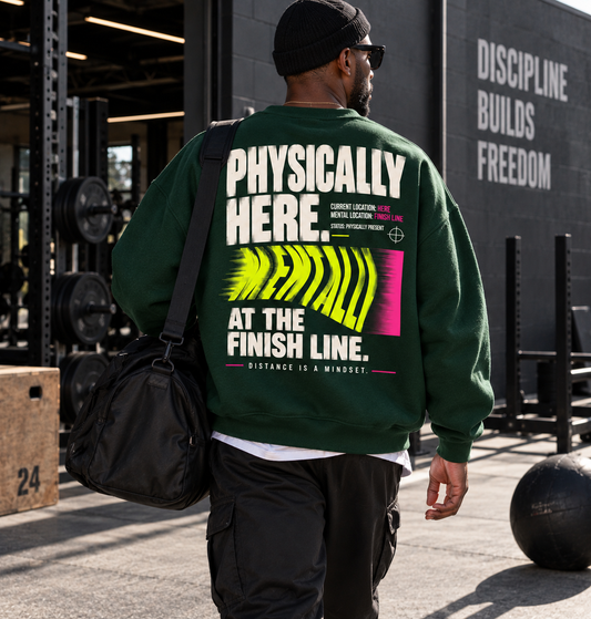 Race Scoop Physically Here Mentally at the Finish Line green crewneck worn by an athlete arriving for training, featuring bold finish line inspired back artwork.