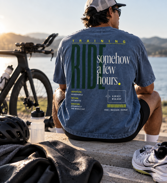 Race Scoop Ride Somehow a Few Hours blue graphic tee worn by a cyclist during a post ride break, featuring bold endurance cycling back artwork.