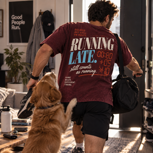Race Scoop Running Late maroon graphic tee worn by a runner rushing out the door for a workout, featuring playful back artwork about showing up even when life gets in the way.