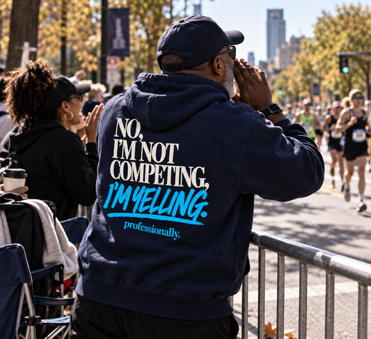 Race Scoop I’m Not Competing I’m Yelling navy hoodie worn by a race supporter cheering from the sidelines, featuring bold Support Crew inspired back artwork.